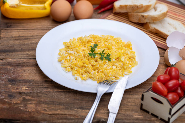 fresh scrambled eggs on white plate on breakfast table - Photo, Image