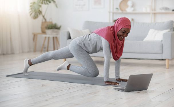 Домашній спорт для мусульманських жінок. Дама в хіджабі виганяє у вітальні
 - Фото, зображення