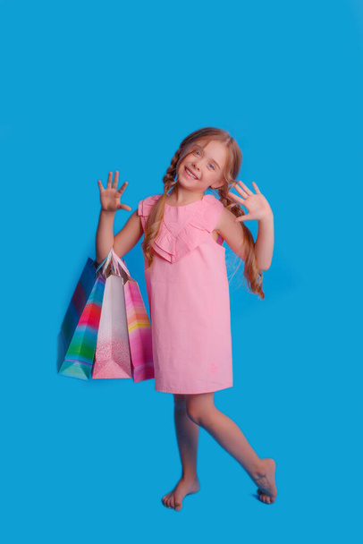 Dziewczyna z mnóstwem toreb na zakupy pozujących na niebieskim tle - Zdjęcie, obraz
