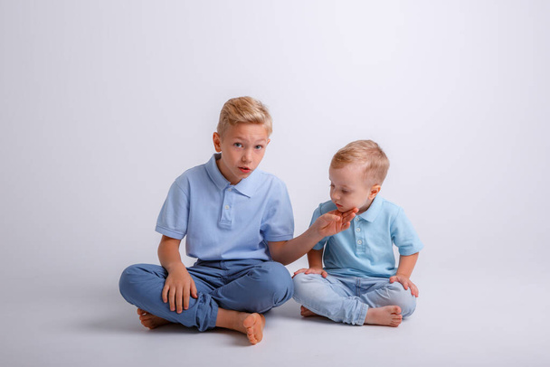 dva chlapci sedící na podlaze a dívající se do kamery - Fotografie, Obrázek