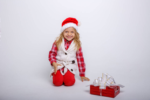 αξιολάτρευτο παιδί που ποζάρει στο στούντιο με χριστουγεννιάτικο δώρο - Φωτογραφία, εικόνα