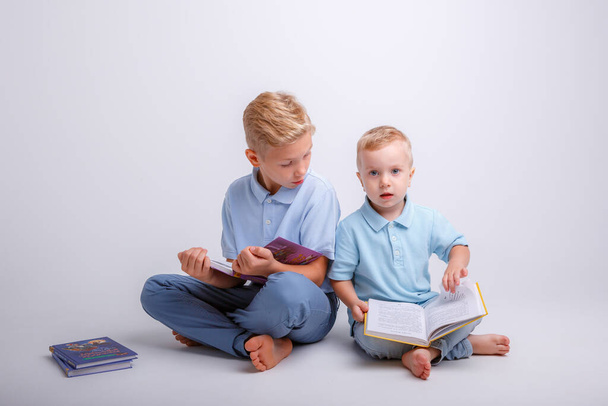 dos niños pequeños sentados en el suelo y leyendo un libro - Foto, Imagen