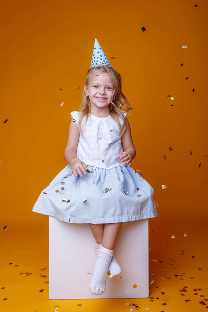 aranyos születésnapi lány pózol stúdió ellen narancs háttér - Fotó, kép