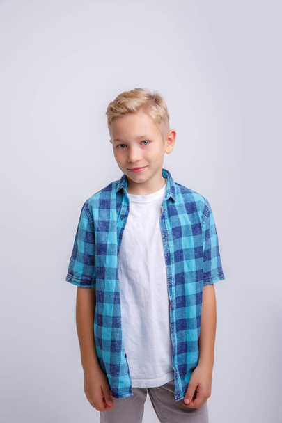Porträt eines niedlichen Jungen in einem blauen T-Shirt auf weißem Hintergrund - Foto, Bild