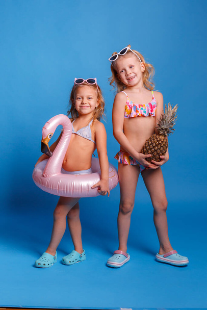 two little girls in swimsuits with pineapple and lifebuoy - Fotografie, Obrázek