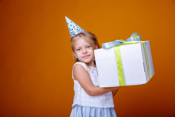 birthday girl posing with gift box against orange in studio - Zdjęcie, obraz