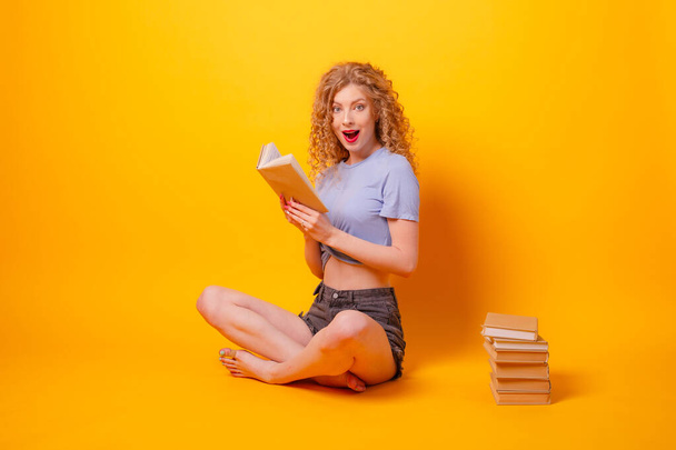 beautiful woman reading book against orange  - Foto, Imagen
