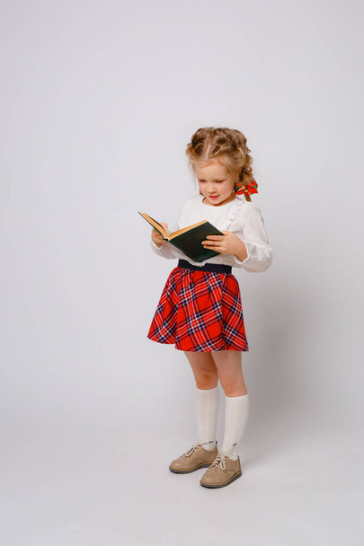 dziecko dziewczyna w szkole mundur trzymać książka biały tło  - Zdjęcie, obraz