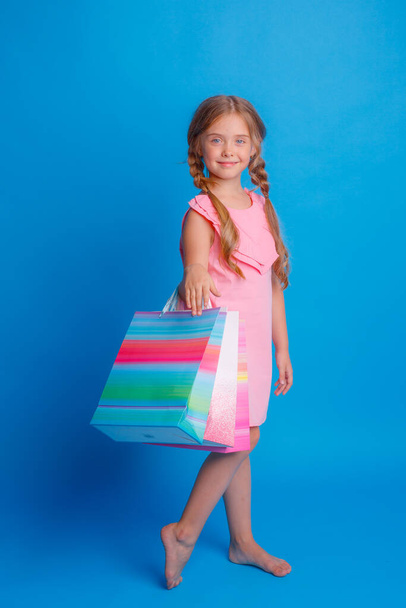 Una ragazza con un sacco di borse della spesa in posa su uno sfondo blu - Foto, immagini