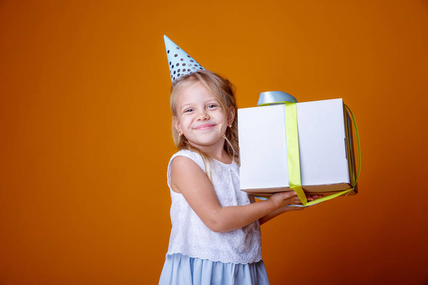 birthday girl posing with gift box against orange in studio - Photo, Image