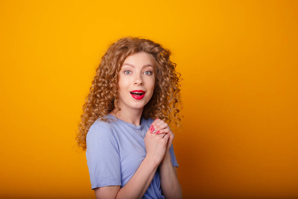 emotional young lady posing in studio against orange background - Φωτογραφία, εικόνα