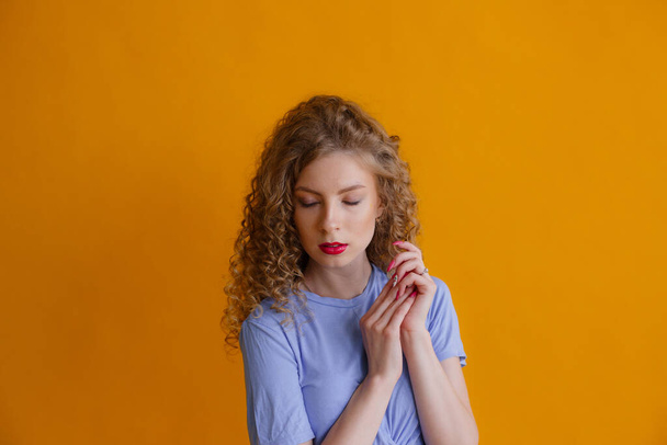 emotional young lady posing in studio against orange background - Photo, image