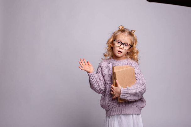 une petite fille blonde en lunettes, tenant un livre  - Photo, image