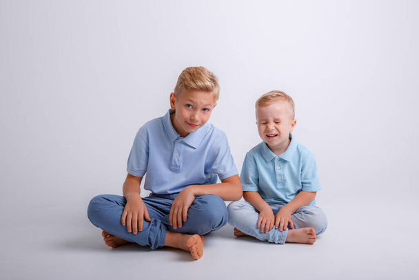 dva chlapci sedící na podlaze a dívající se do kamery - Fotografie, Obrázek