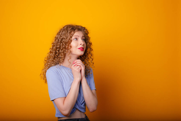 jeune femme émotionnelle posant en studio sur fond orange - Photo, image