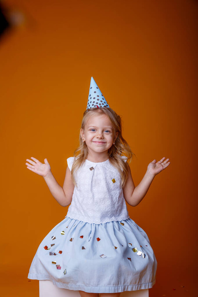 χαριτωμένο κορίτσι γενεθλίων ποζάρουν στο στούντιο με φόντο πορτοκαλί - Φωτογραφία, εικόνα