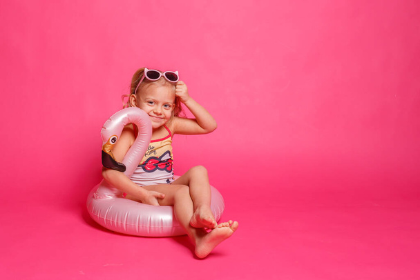 cute little girl in swimsuit with lifebuoy in shape of flamingo - Foto, Imagen