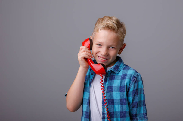 little boy with old  phone on a gray background - Foto, Imagen