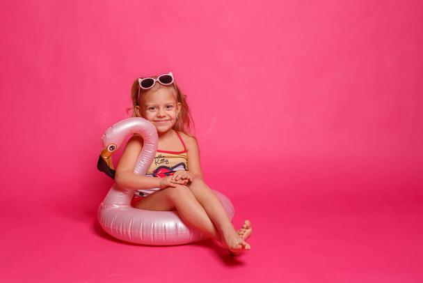 cute little girl in swimsuit with lifebuoy in shape of flamingo - 写真・画像