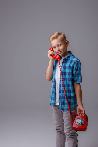 portrétista s telefonem na modrém pozadí. malá holčička mluví po starém telefonu. - Fotografie, Obrázek