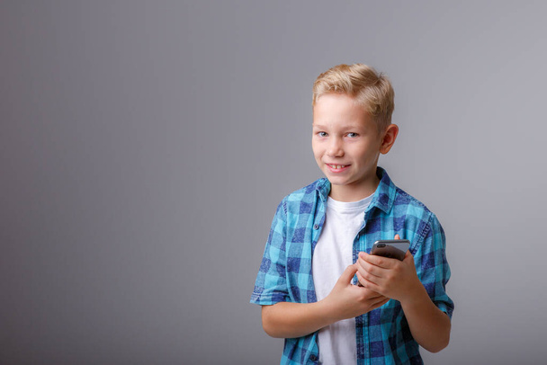 スマートフォンを使ったプレイシャツを着たファッショナブルな男の子 - 写真・画像