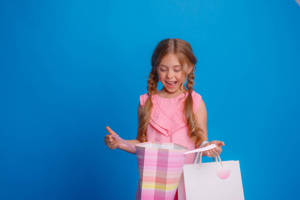 Dziewczyna z mnóstwem toreb na zakupy pozujących na niebieskim tle - Zdjęcie, obraz