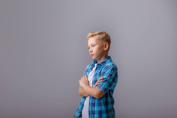 portrait of a boy in a blue shirt on a gray background - Zdjęcie, obraz