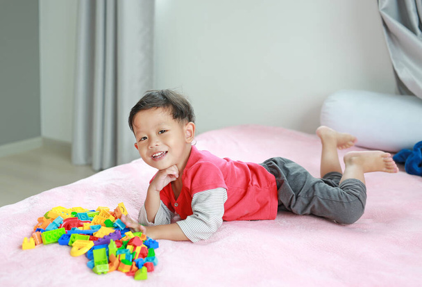 Adorable asian little baby boy playing colorful plastic blocks and lying on bed. - Fotografie, Obrázek
