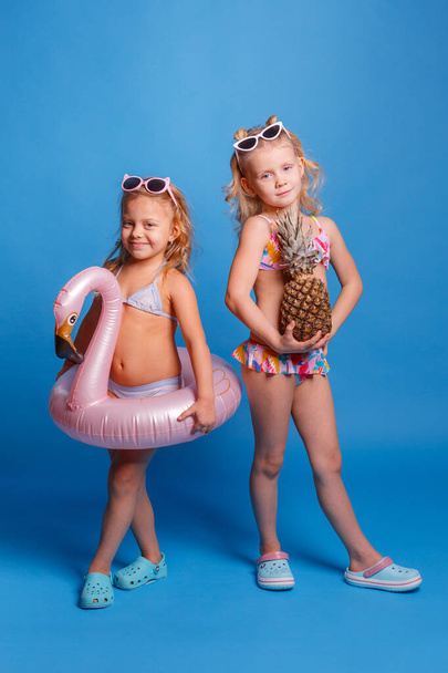 two little girls in swimsuits with pineapple and lifebuoy - Фото, изображение