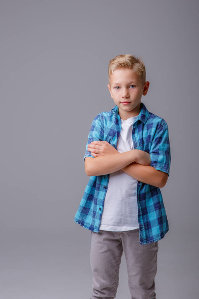 niño con una camiseta azul en el cuello y mira a la cámara sobre fondo blanco - Foto, Imagen