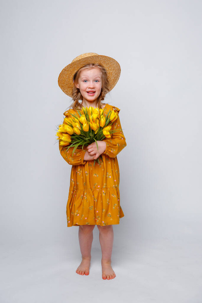 dziewczynka w żółtej sukience z bukietem kwiatów na białym tle - Zdjęcie, obraz