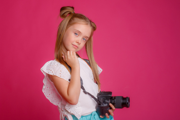 Portrait d'une voyageuse, parlant de voyage, tenant un appareil photo dans ses mains, sur un fond rose - Photo, image
