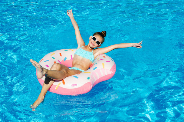 Cute smiling little girl in swimming pool with rubber ring. Child having fun on vacation in summertime - Φωτογραφία, εικόνα