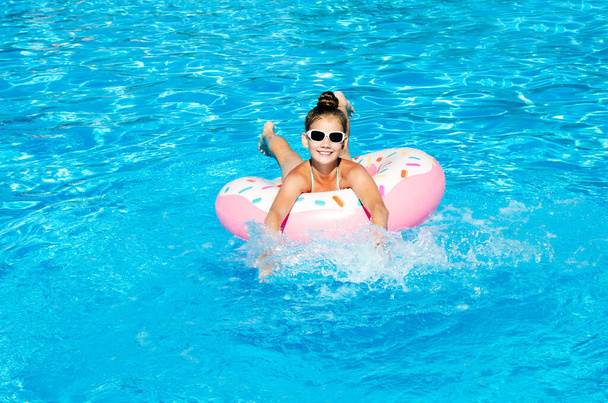 Cute smiling little girl in swimming pool with rubber ring. Child having fun on vacation in summertime - Φωτογραφία, εικόνα