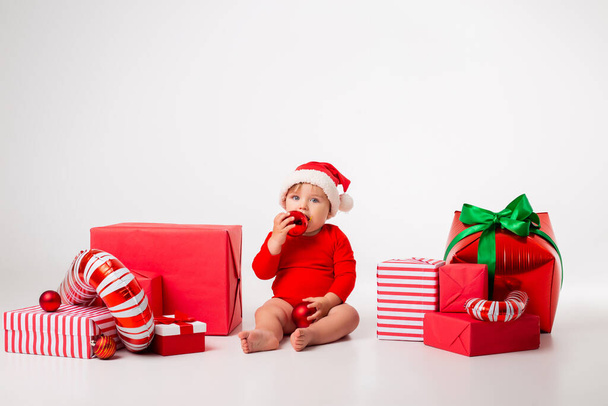 Lindo bebé Santa con cajas de regalo sonriendo sobre un fondo blanco. el concepto de Navidad. Espacio para texto - Foto, Imagen