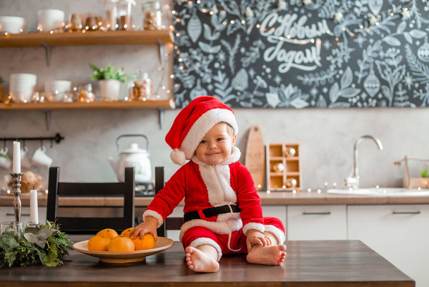 Маленька Санта сидить на кухні будинку, напис на графічній дошці російською мовою "щасливий новий рік"."! - Фото, зображення