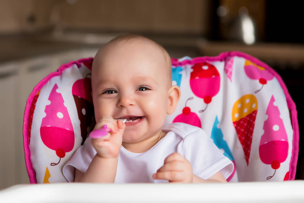 Niedliches kleines Baby mit Nahrung im bunten Babystuhl - Foto, Bild