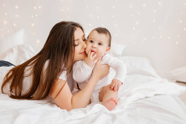 Boldog fiatal anya ölelés kisgyermek az ágyban - Fotó, kép