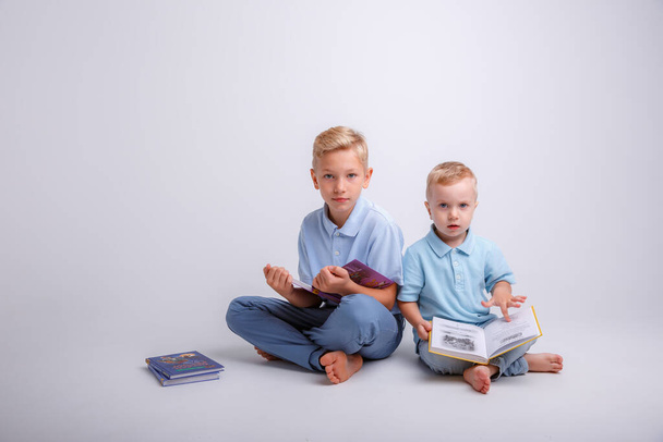 dwoje małych dzieci siedzących na podłodze i czytających książkę - Zdjęcie, obraz
