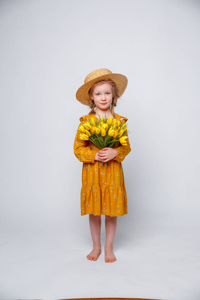 little girl in a yellow dress with a bouquet of flowers on a white background - Photo, Image