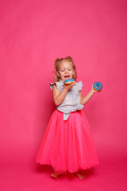 wesoła dziewczynka z pączkami na różowym tle  - Zdjęcie, obraz