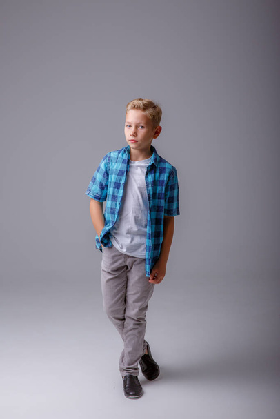 portrait of young boy with blue jeans on grey background - Fotoğraf, Görsel