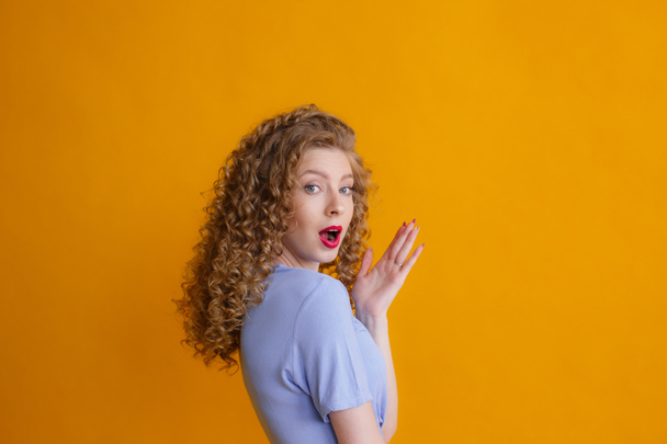 emotional young woman posing in studio against orange background - Photo, Image