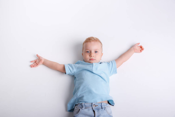 aranyos kisfiú egy kék ing és fehér pólók egy könnyű háttér - Fotó, kép