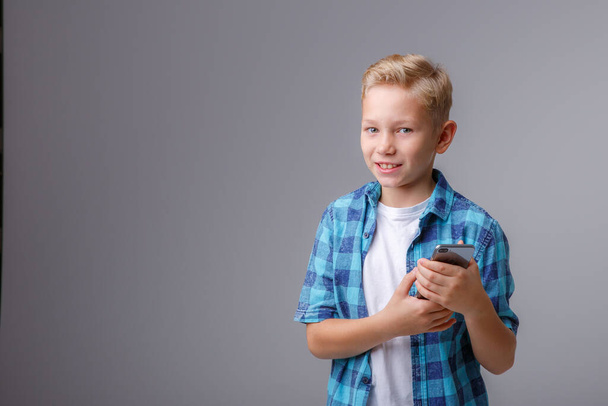スマートフォンを使ったプレイシャツを着たファッショナブルな男の子 - 写真・画像