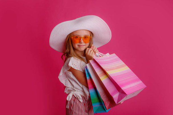 a little Girl with a lot of shopping bags on a pink background in the Studio, happy - Foto, immagini