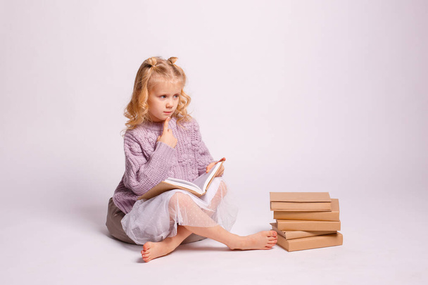 Yerde oturmuş kitap okuyan tatlı bir kız.  - Fotoğraf, Görsel
