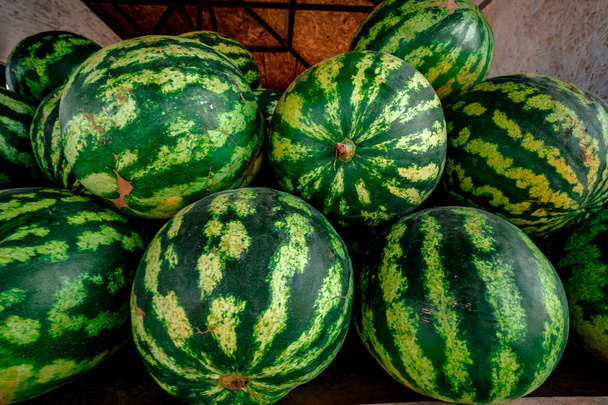 Sok nagy édes zöld görögdinnye és egy vágott görögdinnye. - Fotó, kép