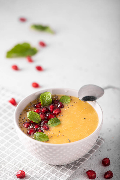 mango and pomegranate smoothie with mint leaves in a gray bowl - Фото, зображення