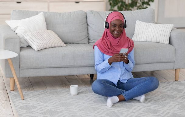 Islamic Women Leisure. Religious Black Lady In Hijab Listening Music At Home - Foto, immagini